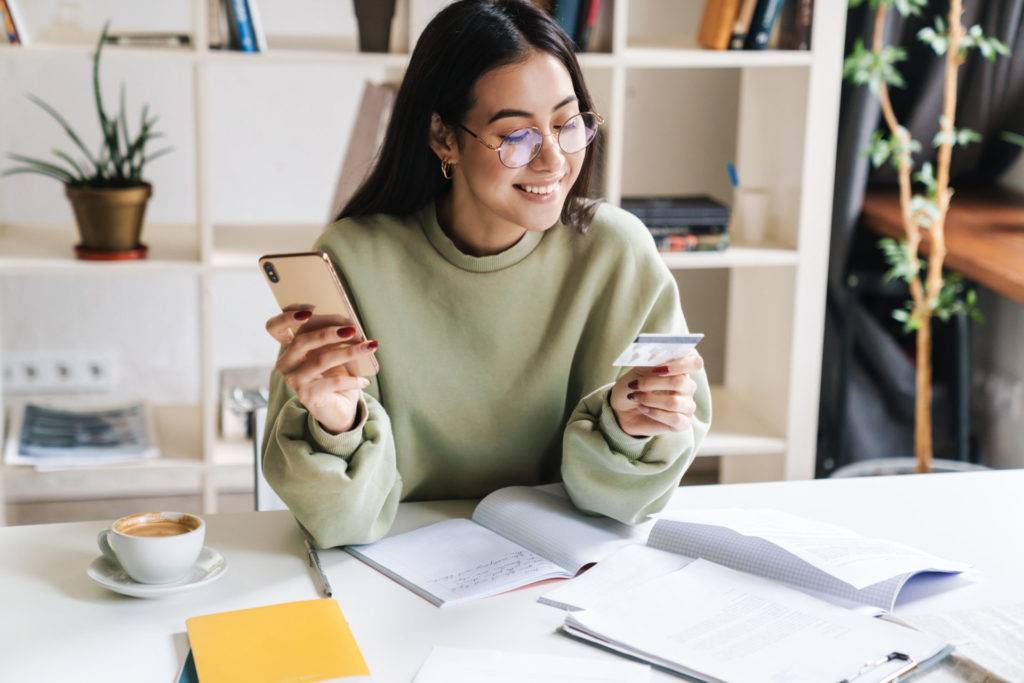 Happy young woman holding credit card