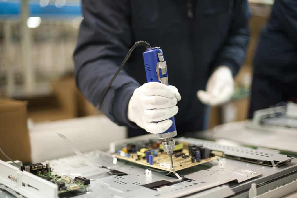 Worker screwing a motherboard down with an electric screwdriver