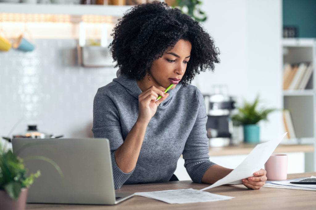 Business woman working with computer while consulting some invoices