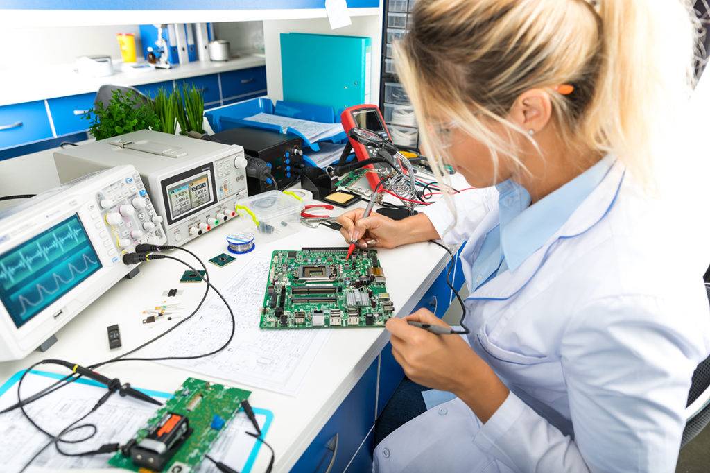 Female electronic engineer testing computer motherboard